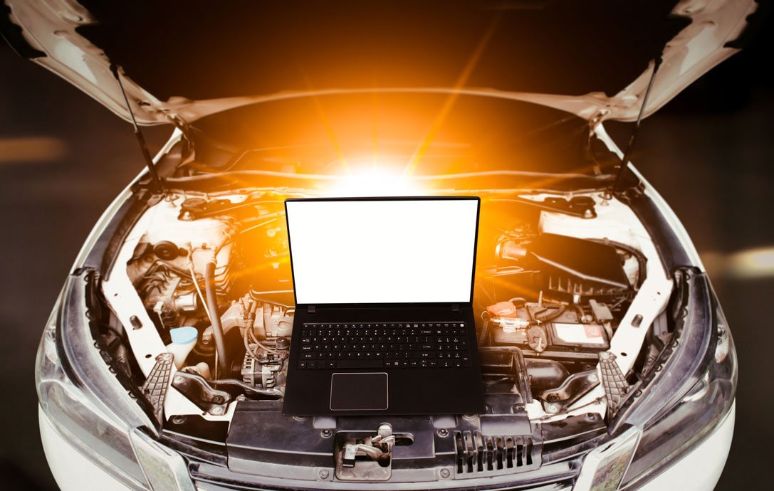 A latop sits on top of a car engine whilst its being remapped